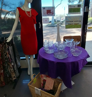 A mannequin with a red dress overlooking a table with glassware